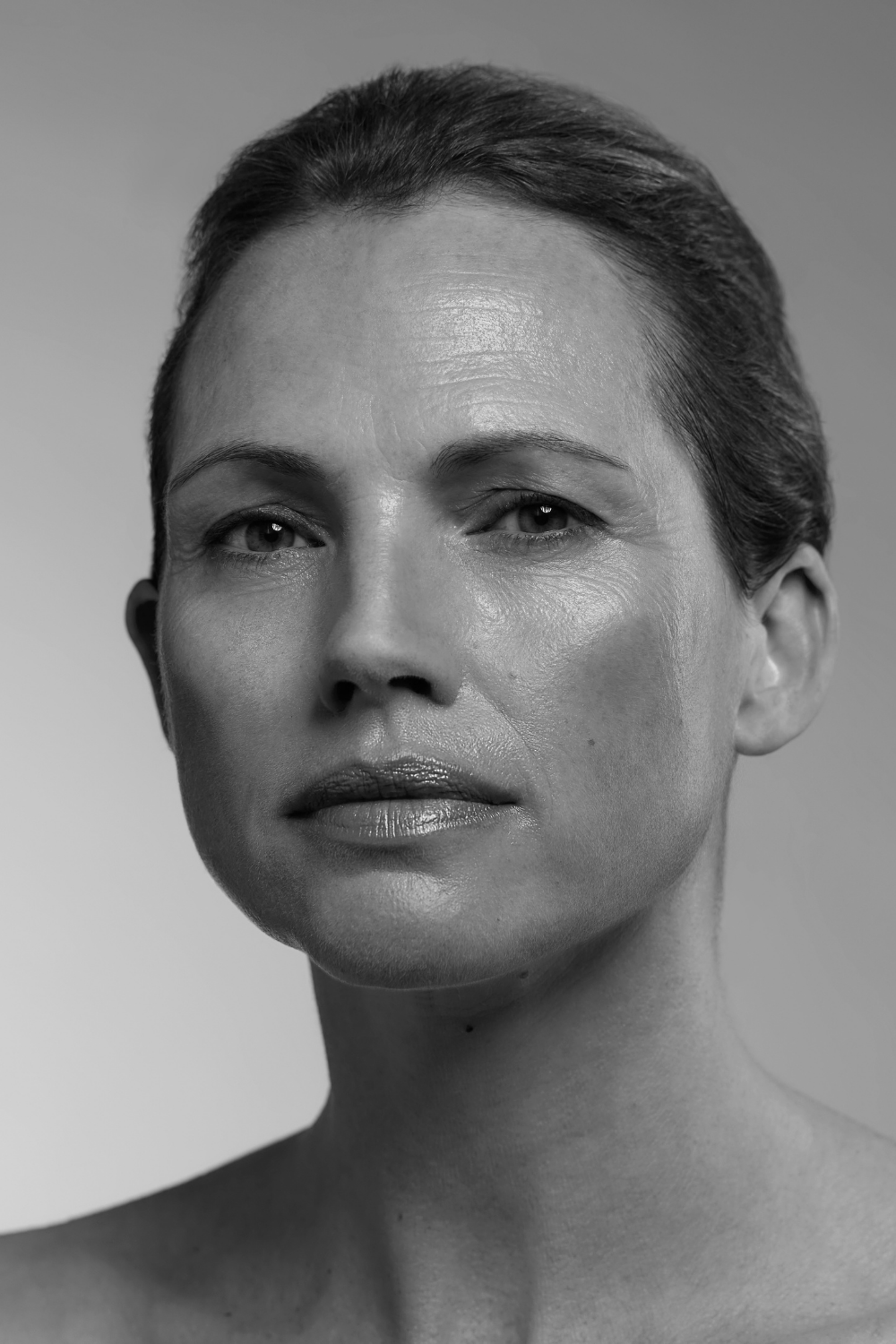 Black and white portrait of a woman with a neutral expression on a plain background