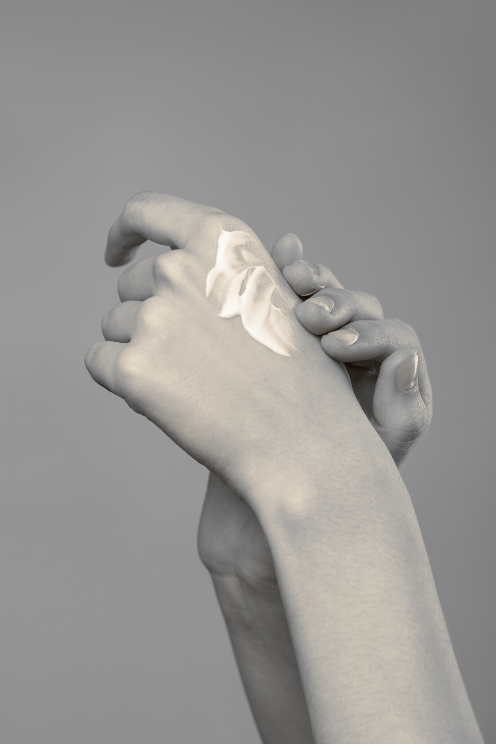 Gray marble sculpture of two hands holding each other against a gray background